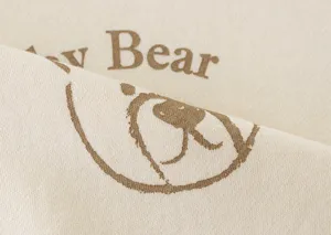 Close-up fabric detail of beige children sweatshirt featuring cute brown bear print design.