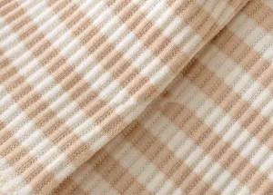 Close-up detail of soft ribbed knit fabric in white and beige stripe design for baby clothing.