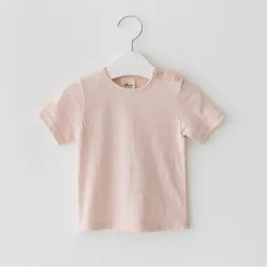 Detalle de camiseta de manga corta rosa lisa para bebés con cuello redondo y botones.