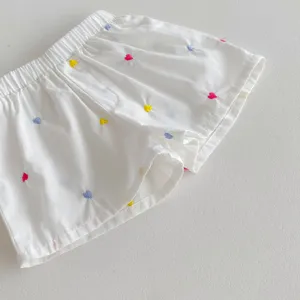 Vista dettagliata di pantaloncini bianchi da bambina con ricami di cuori e vita elastica.