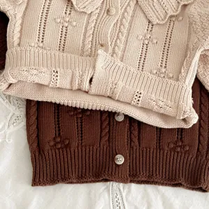 Close-up detail of infant cotton knitted cardigan with cute doll collar and classic cable knit.