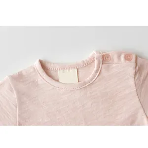 Primer plano de los detalles del escote y botones en el hombro de la camiseta.