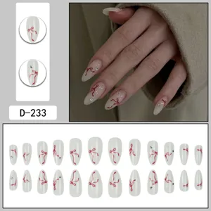 Handmade press-on nails detail showing exquisite red bow and sparkling rhinestone accents.