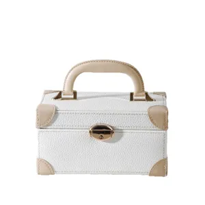 White leather storage box with beige handle and gold lock, portable makeup and jewelry case.