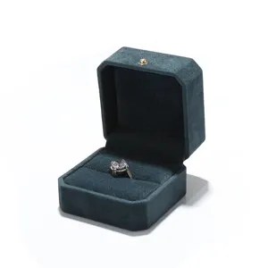 Caja de joyería octogonal de terciopelo verde oscuro con anillo elegante para exhibición.