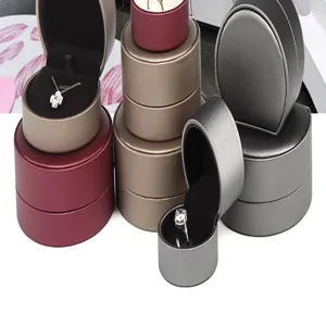 Detail view of round brushed leather jewelry box featuring ring and necklace display.