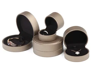 Detail view of round brushed leather jewelry boxes with soft black velvet interior lining.