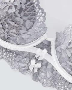 Close-up detail of grey lace bra featuring delicate white trim and cute bow decorations.