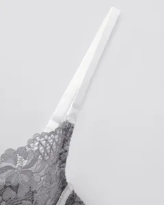 Close-up detail of women grey lace bra with adjustable white shoulder straps texture display.