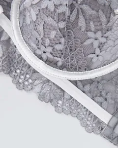 Detailed view of women's grey lace bra with delicate floral patterns and white trim, elegant style.