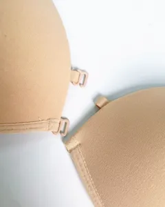 Detailopname van een nude bh met voorsluiting die fijne stof en plastic haakje toont.