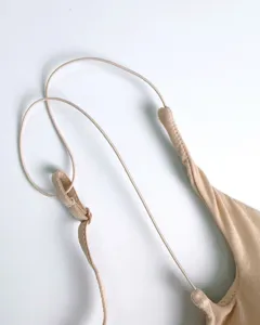 Detailed view of a nude strappy wireless bra, soft fabric and delicate thin cross straps.