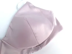 Sujetador de satén sin aro detalle, rosa suave, textura lisa, diseño cómodo sin costuras.