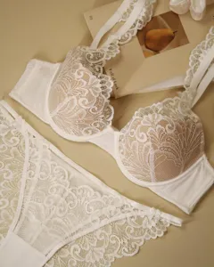 Detailed close-up of exquisite white floral lace lingerie set, elegant French style flat lay.