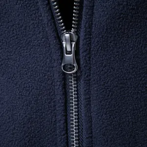 Nahaufnahme des Reißverschlusses einer dunkelblauen Fleecejacke mit weichem Stoff und Metall.