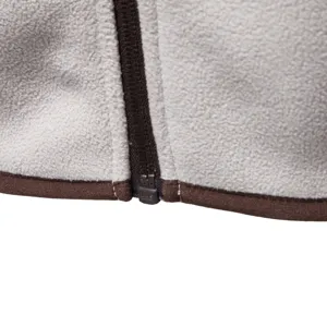 Close-up view of men's fleece jacket zipper and brown trim detail, showing texture.