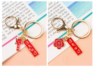 Gros plan détaillé du porte-clés porte-bonheur en métal avec fleur émaillée rouge et pendentif.