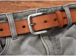 Detailopname van de retro bruine lederen riem met metalen gesp op een grijze jeansbroek.