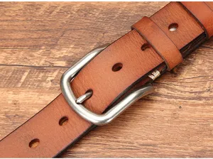 Close-up detail of vintage genuine leather belt with metallic pin buckle and fine stitching.