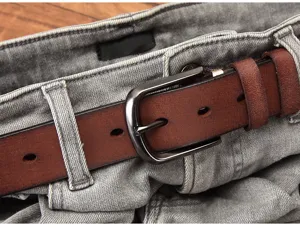 Close-up detail of mens brown genuine leather belt with metal buckle styled with grey jeans