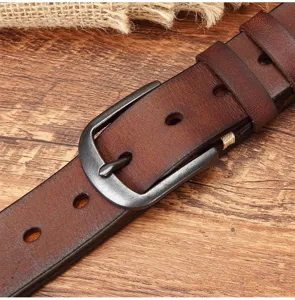 Close-up of men's vintage genuine leather belt with solid metal pin buckle and rich texture.
