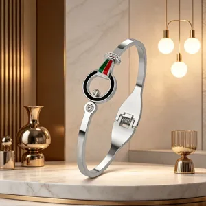 Close-up detail of luxury titanium steel bangle with red green stripe and rhinestone design.