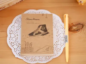 Détail de carnet vintage en papier kraft marron avec illustration de couverture et stylo.