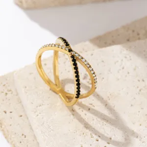 Anillo cruzado bañado en oro con piedras de circonita blancas y negras brillantes.