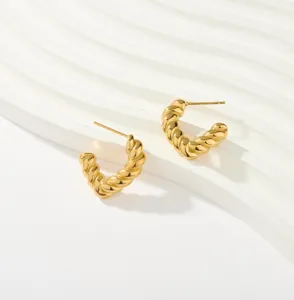 Vista detallada de pendientes de aro retorcidos chapados en oro de 18K con textura pulida.