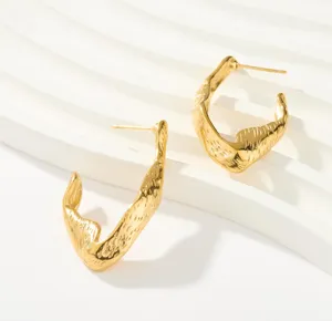 Goldene unregelmäßige strukturierte Ohrringe Nahaufnahme, retro minimalistischer Schmuck.