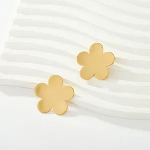 Detalle de pendientes de botón con diseño de flor de cinco pétalos en oro mate cepillado