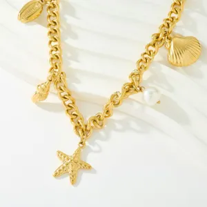Gros plan d'un collier de style océan plaqué or avec des pendentifs coquillage et étoile.
