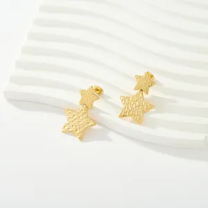 Vista detallada de pendientes de estrella de acero inoxidable chapado en oro con textura martillada