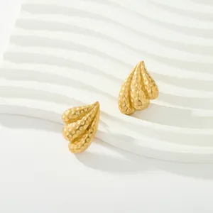 Gros plan sur des boucles d'oreilles clous martelées plaquées or 18k au design texturé unique.