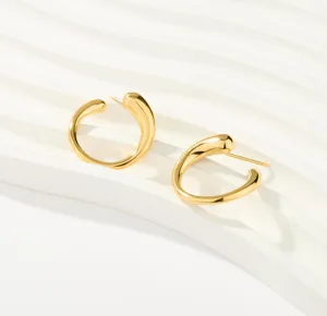 Close-up detail of golden irregular curved open hoop earrings, showcasing the chic shiny texture.