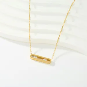 Detalle de collar dorado que muestra el elegante colgante de barra con circones.