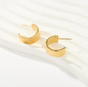 Detalle de pendientes de aro minimalistas en acero de titanio chapado en oro de 18k.