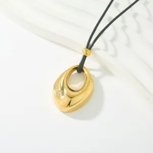 Vista detallada del collar con colgante dorado hueco e irregular con piedras de cristal brillantes.