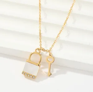 Exquisite gold lock and key pendant necklace detail showcasing white inlay and crystal accents.
