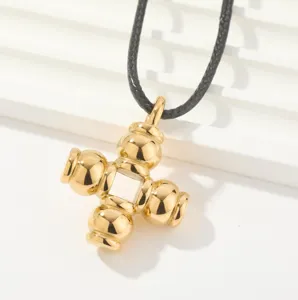 Colgante de cruz geométrica de color oro con collar de cordón negro vista detallada
