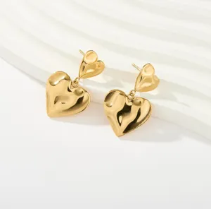 Pendientes de doble corazón dorados, joyas minimalistas de acero inoxidable en detalle.