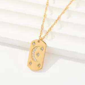 Detalle de un collar de acero de titanio bañado en oro con colgante de luna y estrellas.