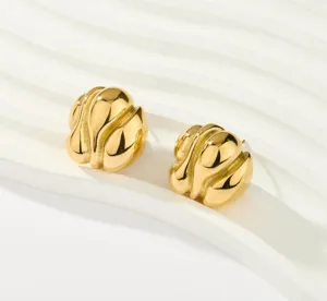 Gros plan de boucles d'oreilles clous dorées texturées irrégulières au design moderne ondulé.