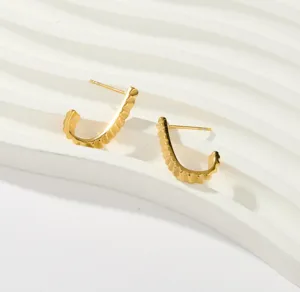 Gold textured crescent hoop earrings detail view, elegant minimalist jewelry accessory.