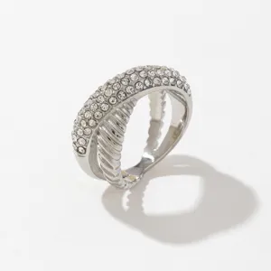 Primer plano detallado del elegante anillo cruzado de pavé de cristal y cuerda plateada.