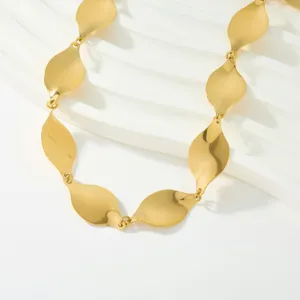 Gros plan d'un collier en chaîne à maillons dorés en forme de feuilles brillantes.