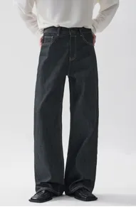 Primo piano dei pantaloni in denim scuro a gamba larga con cuciture a contrasto sul retro.