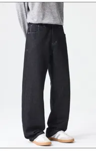 Detail view of loose fit dark denim jeans, showing straight leg design and fabric texture.