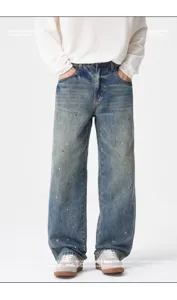 Detail view of men's loose straight fit jeans in vintage blue wash with white paint splatter.