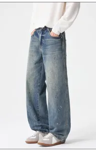 Detail shot of vintage wash paint splatter loose straight-leg denim jeans for men.